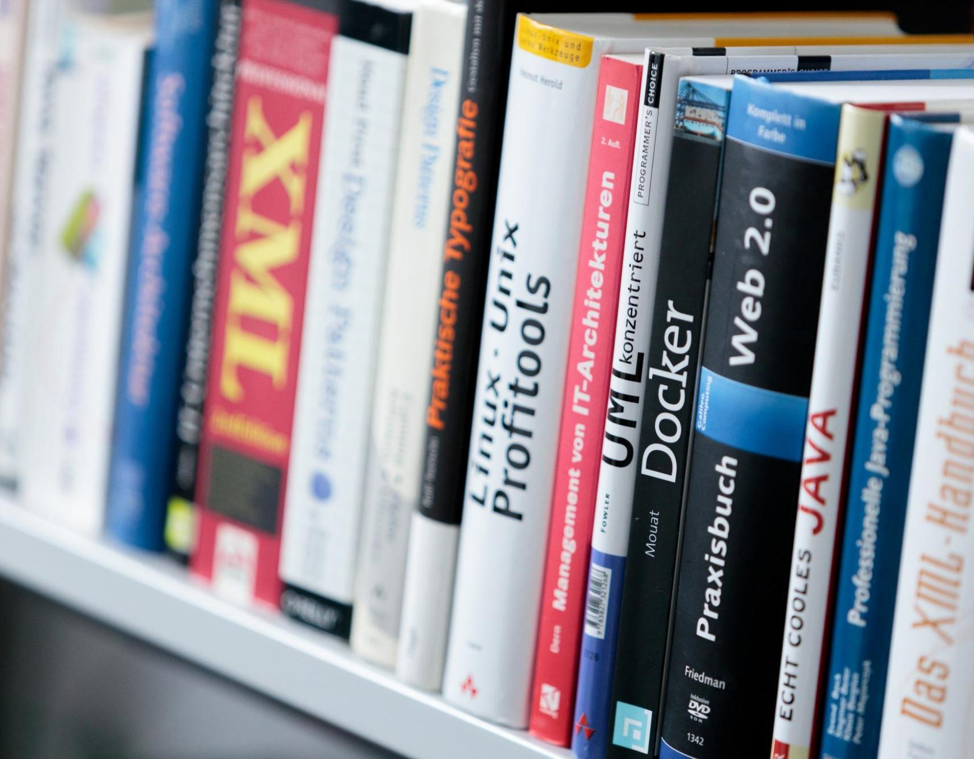 Das Bild zeigt ein Regal mit Büchern zu Themen Softwarearchitektur und  verschiedenen Programmiersprachen