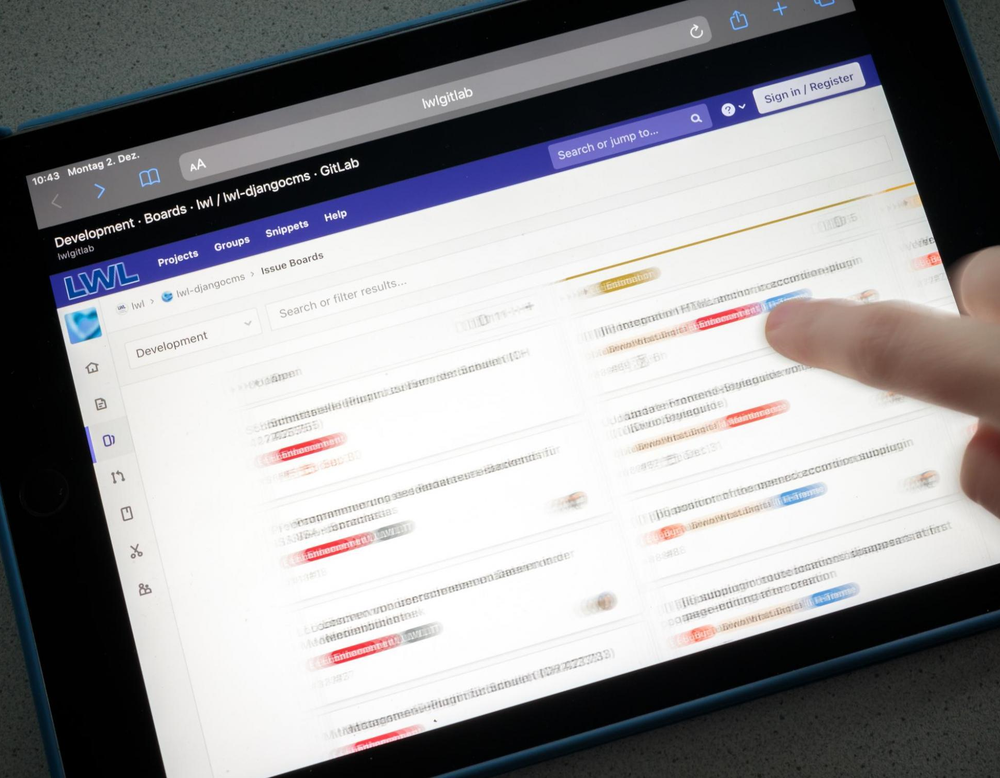 Das Bild zeigt, wie ein Finger über ein iPAD wischt, auf dem in der Kanban-Methode gearbeitet wird